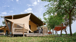 Safaritent Villatent Wood op Camping Nautic Almata in Spanje met houten terras en hangmat in de tuin.