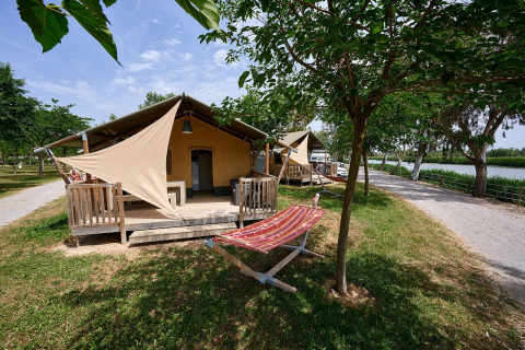 Tenda safari Villatent Wood al Camping Nautic Almata in Spagna, veranda ombreggiata e vista sul fiume.