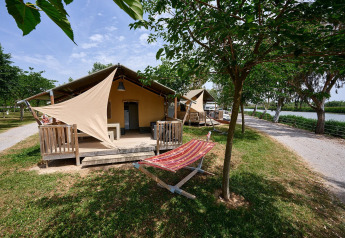 Tenda safari Villatent Wood al Camping Nautic Almata in Spagna, veranda ombreggiata e vista sul fiume.