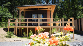 Lodge Edelweiss aan de Ossiacher See in Oostenrijk, met bloemen op de voorgrond en bos erachter.
