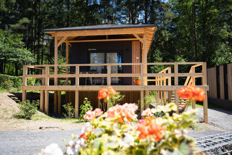 Lodge Edelweiss en Ossiacher See, Austria, rodeado de bosque con flores en primer plano.