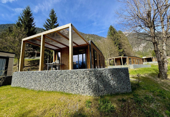 Panorama Lodge en Pressegger See, Austria, con cabañas modernas de madera, terraza y vistas a las montañas.