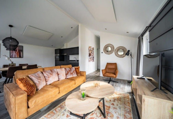 Salotto moderno nel lodge Hackfort a Vakantiepark Aan de Maas, Paesi Bassi, con arredi marroni accoglienti.