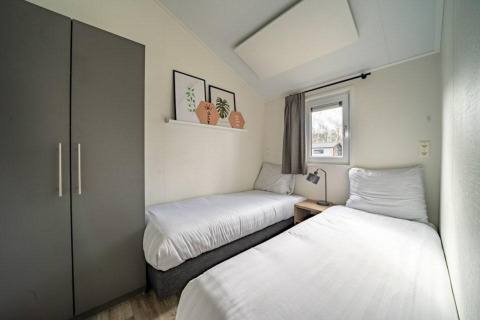 Moderne slaapkamer met twee eenpersoonsbedden in Hackfort lodge, Vakantiepark Aan de Maas, Nederland.