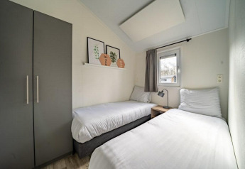Camera moderna con due letti singoli nella lodge Hackfort al Vakantiepark Aan de Maas, Paesi Bassi.