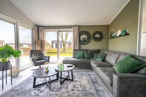 Modern living room in Hackfort lodge at Vakantiepark Aan de Maas, Netherlands, with green and grey decor.