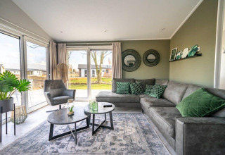 Moderne woonkamer in Hackfort-lodge bij Vakantiepark Aan de Maas, Nederland, met groen en grijs interieur.