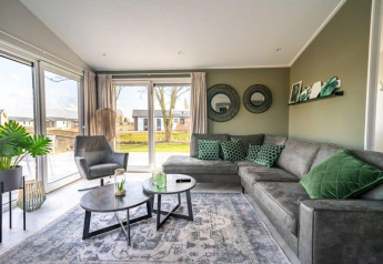 Moderne woonkamer in Hackfort-lodge bij Vakantiepark Aan de Maas, Nederland, met groen en grijs interieur.