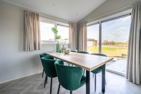 Helles Esszimmer in der Hackfort-Lodge im Vakantiepark Aan de Maas, Niederlande, mit grünen Stühlen.