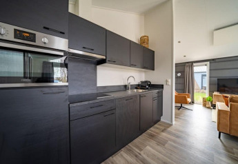 Moderne zwarte keuken in de Hackfort lodge met open woonkamer en houten vloer in Nederland.