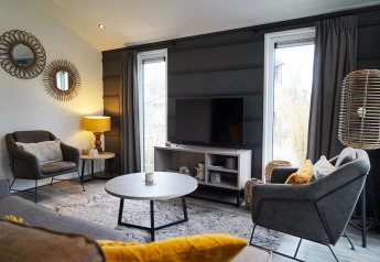 Moderne woonkamer in Hackfort-lodge bij Vakantiepark Aan de Maas, Nederland, met stijlvolle inrichting en licht.