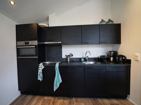 Moderne zwarte keuken in een Hackfort-lodge op Vakantiepark Aan de Maas in Nederland, met apparatuur.