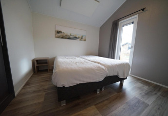 Camera da letto nella lodge Hackfort al Vakantiepark Aan de Maas, Paesi Bassi, con letto matrimoniale e finestra.