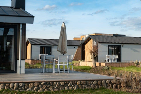 Terrazas de cabañas modernas en Hackfort, Vakantiepark Aan de Maas, Países Bajos, con asientos al aire libre.