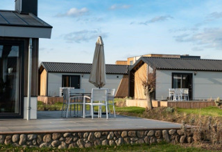 Moderne lodges Hackfort bij Vakantiepark Aan de Maas, Nederland, met terrassen en tuinmeubilair buiten.