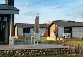 Moderne lodges Hackfort bij Vakantiepark Aan de Maas, Nederland, met terrassen en tuinmeubilair buiten.