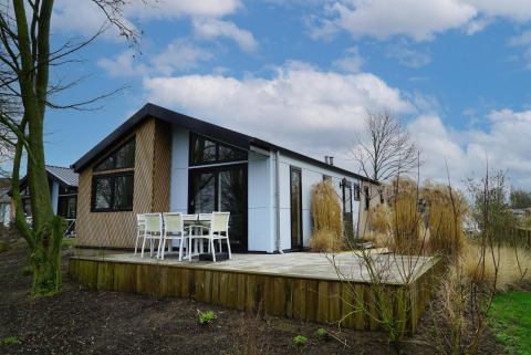 La cabaña Hackfort en Vakantiepark Aan de Maas, Países Bajos, con terraza de madera y sillas exteriores.