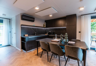 Cocina y comedor modernos en la cabaña Wulfenia en Ossiacher See, Austria, con decoración oscura elegante.