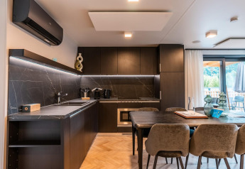 Cocina y comedor modernos en la lodge Wulfenia en Ossiacher See, Austria, con vista a la naturaleza exterior.