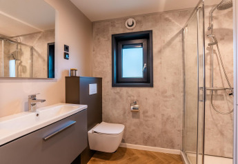 Moderne badkamer met douche, wastafel, zwevend toilet en raam in Wulfenia aan de Ossiacher See, Oostenrijk.