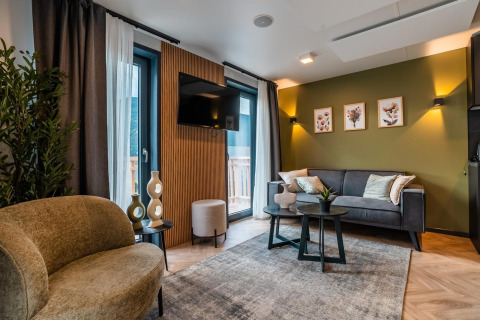 Salón moderno en el lodge Seerose junto al lago Ossiacher See en Austria, con decoración elegante y pared verde.