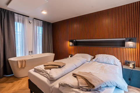 Moderne kamer in lodge Seerose bij Ossiacher See, Oostenrijk, met dubbel bed en vrijstaand bad.