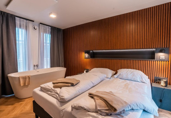 Camera moderna al lodge Seerose sul lago Ossiacher, Austria, con letto matrimoniale e vasca da bagno.