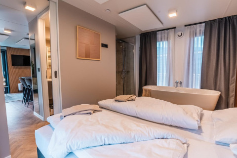 Moderne lodgekamer in Seerose bij Ossiacher See, Oostenrijk, met bed, bad en stijlvolle aankleding.
