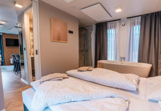 Moderne lodgekamer in Seerose bij Ossiacher See, Oostenrijk, met bed, bad en stijlvolle aankleding.