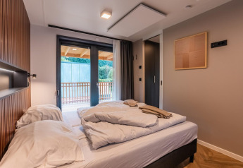 Camera moderna al lodge Seerose sull'Ossiacher See in Austria, con letto matrimoniale e vista balcone.