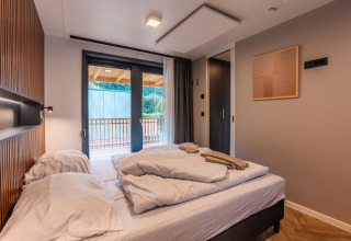 Dormitorio moderno en la lodge Seerose en Ossiacher See, Austria, con cama doble y balcón con vistas.