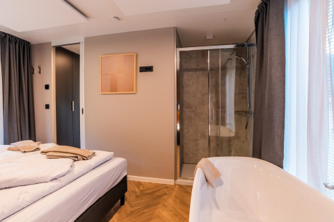 Moderne kamer in lodge Seerose aan de Ossiacher See, Oostenrijk, met bed, douche en vrijstaand bad.