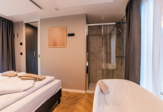Moderne kamer in lodge Seerose aan de Ossiacher See, Oostenrijk, met bed, douche en vrijstaand bad.