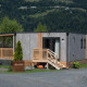 Lodge Enzian ved søen, omgivet af grønne træer og bjerge, med moderne facade og træterrasse.