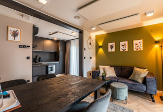 Alojamiento moderno en Ossiacher See, Austria, con sala abierta, cocina y pared verde decorada con arte floral.