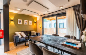 Salón moderno en la lodge Enzian en Ossiacher See, Austria, con mesa de comedor, sofá y acceso al balcón.