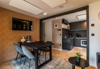 Zona de comedor y sala moderna en la Enzian lodge en Ossiacher See, Austria, con cocina elegante al fondo.