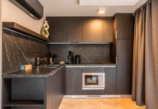 Cocina pequeña y moderna de madera oscura y mármol negro en Enzian en Ossiacher See, Austria.
