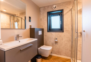 Baño moderno en la lodge Enzian junto al lago Ossiacher See en Austria, con ducha, ventana y lavabo.