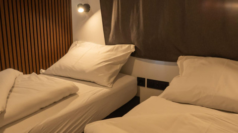Dos camas individuales con sábanas blancas y almohadas en Enzian Lodge, Ossiacher See, Austria, de noche.