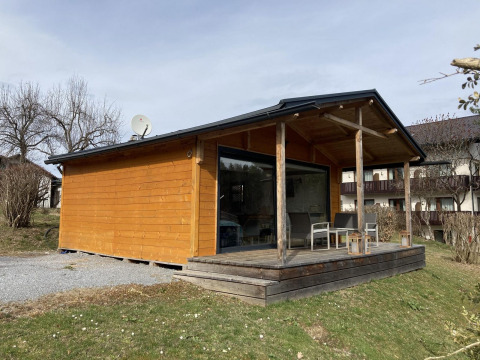 Vista exterior de Stuga 2, una acogedora cabaña de madera con terraza y sillas en un entorno tranquilo.