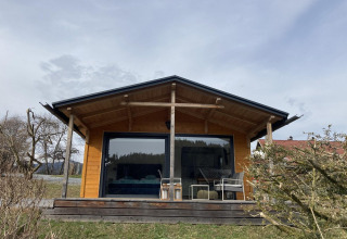 Lodge in legno con ampia veranda e grandi vetrate presso Stuga 2 al Wörthersee, Austria, di giorno.