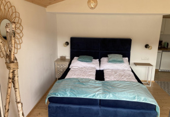 Chambre à Stuga 2 au Wörthersee, Autriche, avec deux lits simples, tables de nuit et décor en bois.