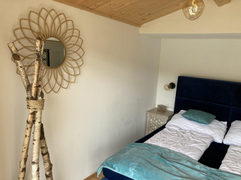 Dormitorio en Stuga 2 en Wörthersee, Austria, con cama doble, techo de madera y espejo decorativo en la pared.
