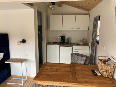 Cozy and modern interior of Stuga 2 at Wörthersee lodge, featuring a kitchenette and wood table.