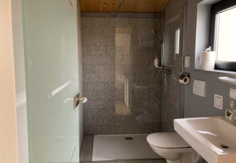 Modernes Badezimmer in Stuga 2 am Wörthersee, Österreich, mit Glasdusche, Toilette und Waschbecken.