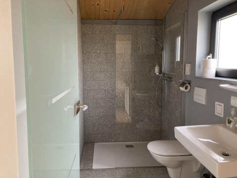 Bagno moderno in Stuga 2 a Wörthersee, Austria, con doccia in vetro, WC, lavandino e finestra.