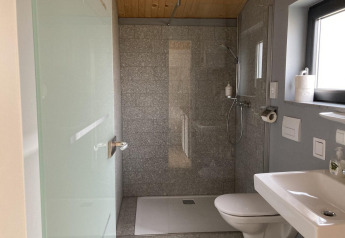 Modernes Badezimmer in Stuga 2 am Wörthersee, Österreich, mit Glasdusche, Toilette und Waschbecken.