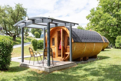 Casa diminuta Tractor cabin de madera con terraza y sillas en un entorno verde y natural.