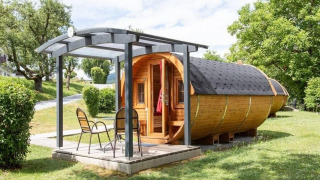 Casa diminuta Tractor cabin de madera con terraza y sillas en un entorno verde y natural.